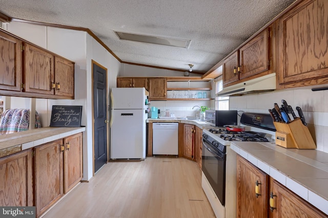 kitchen featuring under cabinet range hood, white appliances, tile countertops, and brown cabinetry