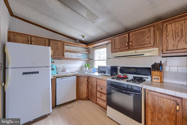 kitchen with under cabinet range hood, open shelves, a sink, white appliances, and lofted ceiling