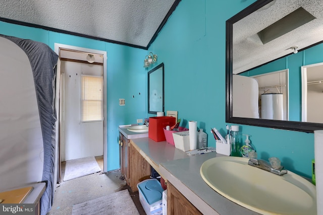 bathroom featuring double vanity, vaulted ceiling, a textured ceiling, and a sink