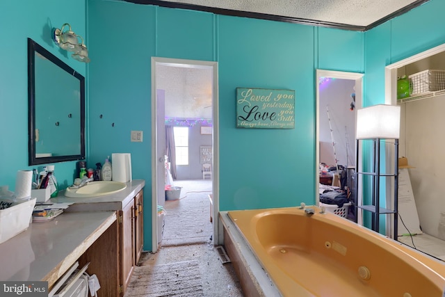 bathroom featuring a textured ceiling, a tub with jets, and vanity