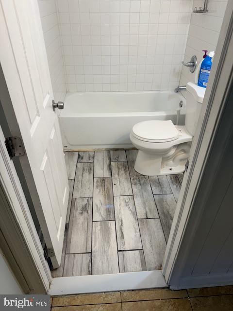 full bath with shower / bath combination, toilet, and wood tiled floor