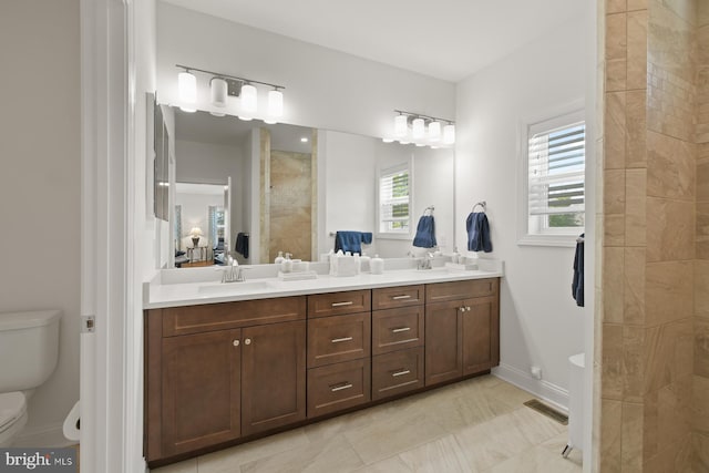 bathroom featuring visible vents, tiled shower, double vanity, a sink, and toilet