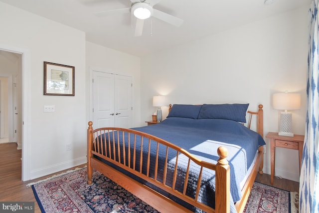 bedroom with a closet, baseboards, wood finished floors, and a ceiling fan