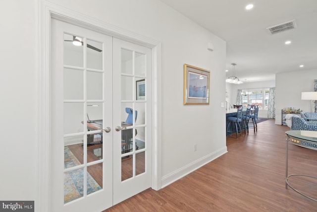 corridor featuring wood finished floors, visible vents, baseboards, recessed lighting, and french doors