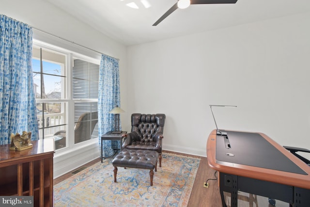 living area featuring visible vents, a ceiling fan, baseboards, and wood finished floors