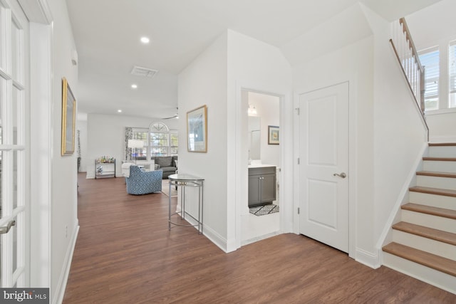 hallway with dark wood finished floors, stairway, recessed lighting, and baseboards