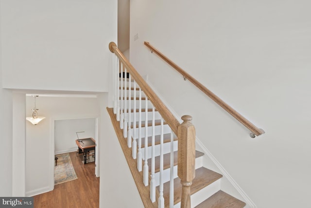 staircase featuring baseboards and wood finished floors