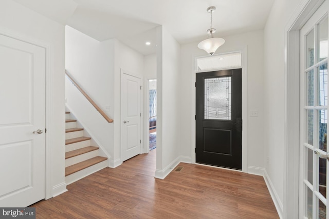 entryway with stairway, visible vents, baseboards, and wood finished floors