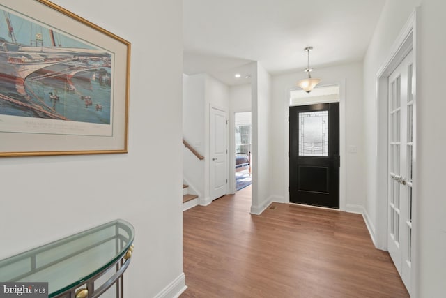 entryway featuring stairway, baseboards, and wood finished floors