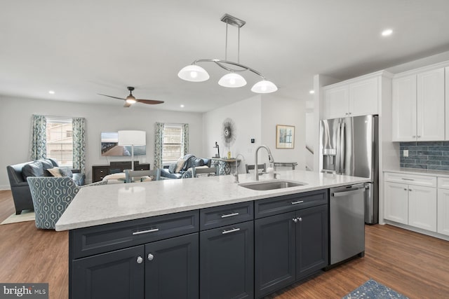 kitchen with open floor plan, stainless steel appliances, dark wood-style floors, white cabinetry, and a sink