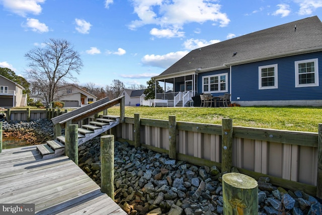 rear view of property with a lawn, a sunroom, a fenced backyard, stairway, and a shingled roof