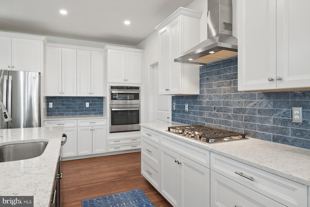 kitchen featuring appliances with stainless steel finishes, white cabinets, and wall chimney range hood