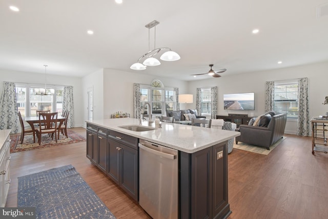 kitchen featuring light wood finished floors, dishwasher, pendant lighting, and a sink