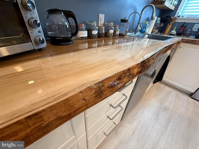 bar with a toaster, light wood-style floors, and a sink