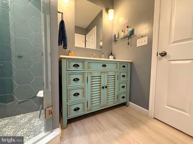 bathroom featuring vanity, wood finished floors, a stall shower, and baseboards