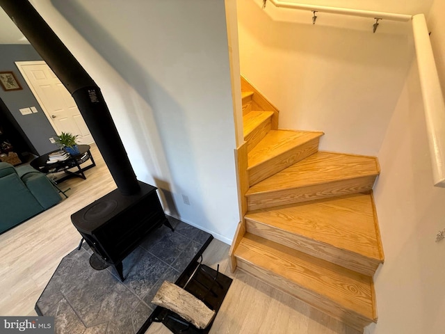 staircase featuring a wood stove and wood finished floors