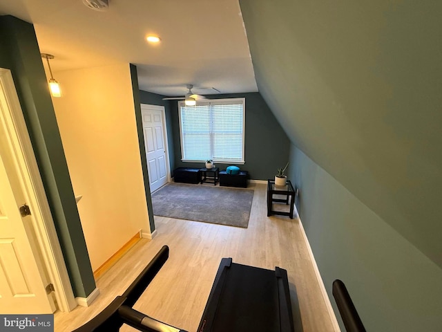 exercise area featuring ceiling fan, baseboards, wood finished floors, and vaulted ceiling