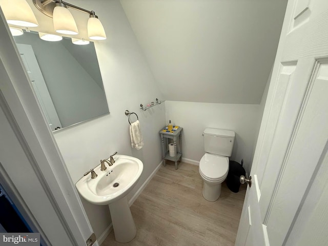 bathroom with baseboards, toilet, lofted ceiling, wood finished floors, and a sink