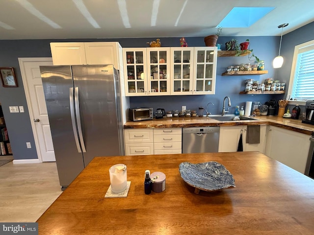 kitchen featuring a sink, stainless steel appliances, white cabinets, and wood counters