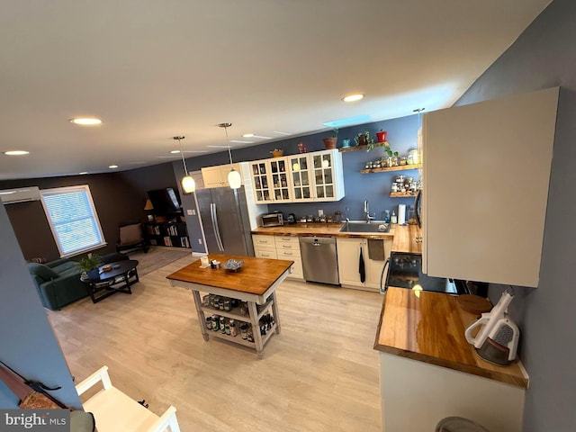 kitchen with open shelves, butcher block countertops, light wood-style floors, appliances with stainless steel finishes, and white cabinetry