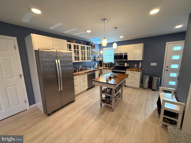 kitchen featuring open shelves, light wood-style flooring, recessed lighting, a sink, and stainless steel appliances