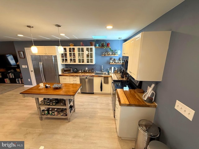 kitchen featuring open shelves, a sink, stainless steel appliances, butcher block countertops, and light wood-style floors