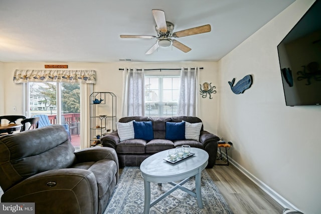 living area with visible vents, a healthy amount of sunlight, baseboards, and wood finished floors