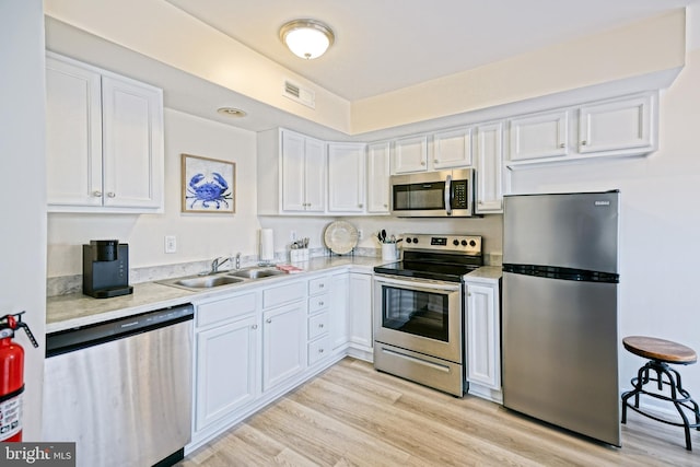 kitchen featuring visible vents, a sink, light countertops, appliances with stainless steel finishes, and white cabinetry