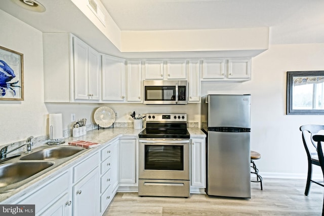 kitchen featuring visible vents, light countertops, white cabinets, stainless steel appliances, and a sink