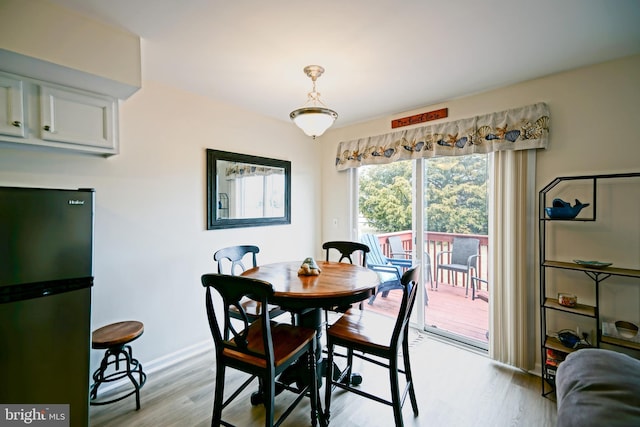 dining space featuring baseboards and light wood finished floors