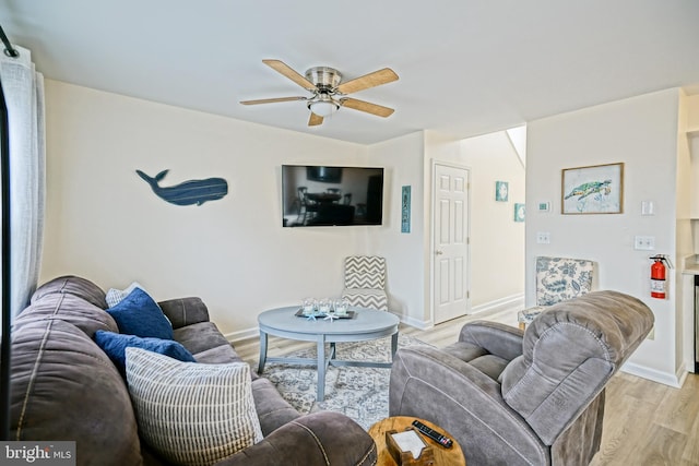 living room with a ceiling fan, light wood-style floors, and baseboards