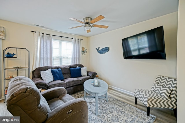 living area with visible vents, baseboards, ceiling fan, and wood finished floors