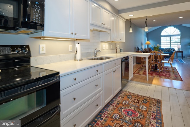 kitchen featuring a sink, black appliances, light countertops, light wood-style floors, and white cabinetry