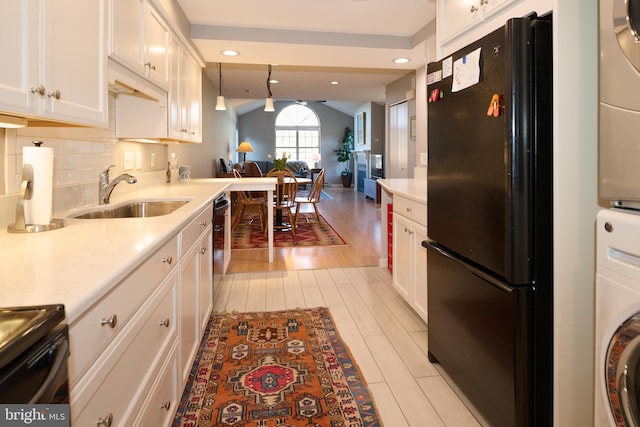 kitchen featuring black appliances, a sink, open floor plan, light countertops, and vaulted ceiling