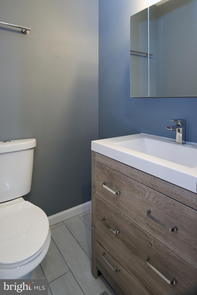 bathroom featuring vanity, toilet, and baseboards