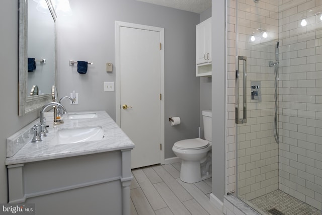 full bath with double vanity, toilet, a stall shower, and wood finish floors