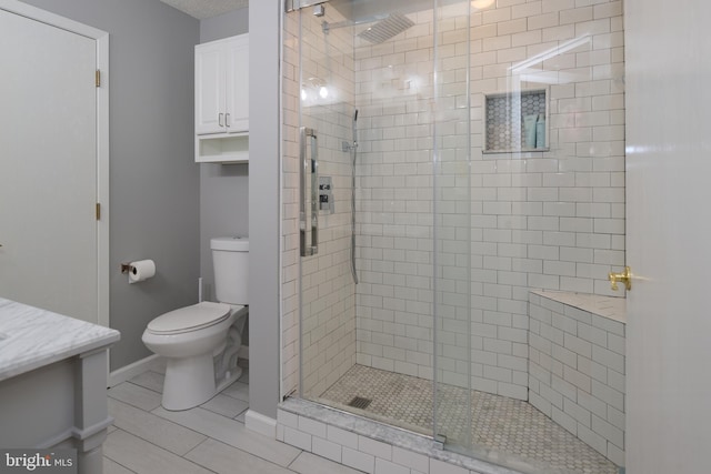 bathroom featuring a shower stall, toilet, vanity, and baseboards