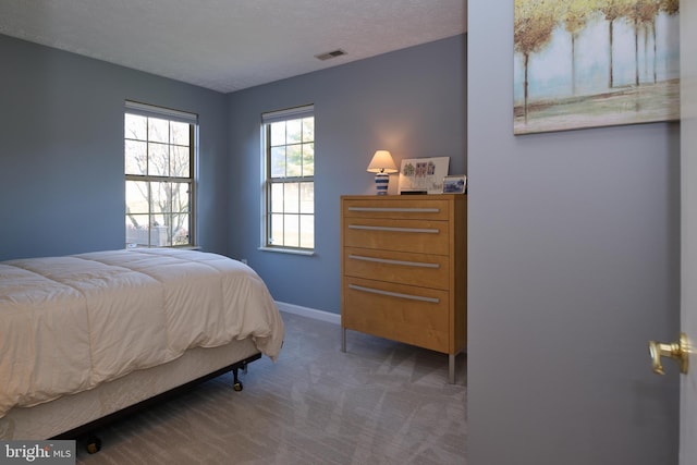 carpeted bedroom with baseboards, visible vents, and a textured ceiling