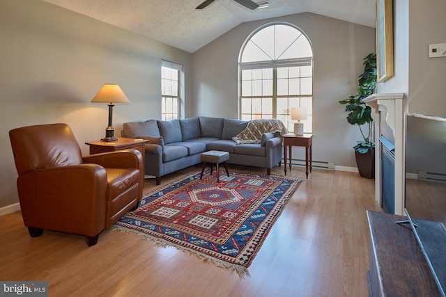 living area with a ceiling fan, baseboards, lofted ceiling, light wood-style floors, and a textured ceiling