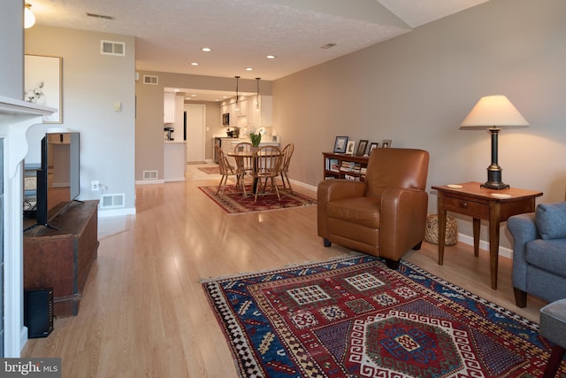 living room featuring visible vents, light wood-type flooring, and baseboards