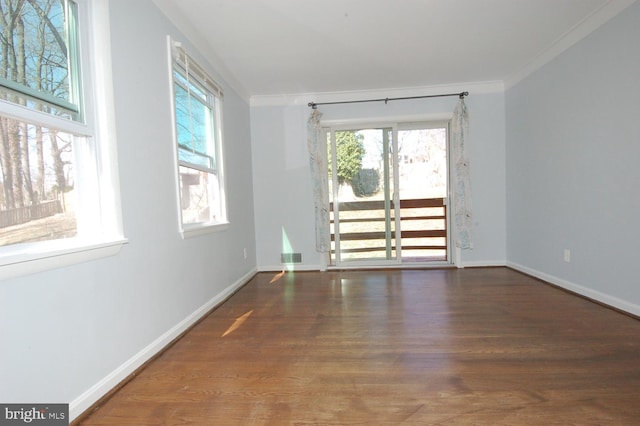 empty room featuring visible vents, wood finished floors, baseboards, and ornamental molding