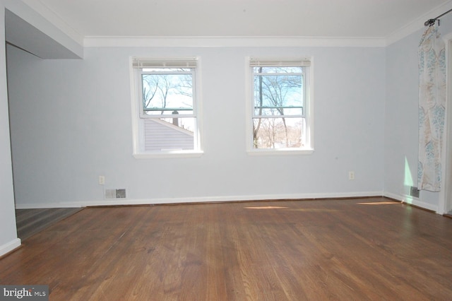 unfurnished room with crown molding, wood finished floors, visible vents, and baseboards