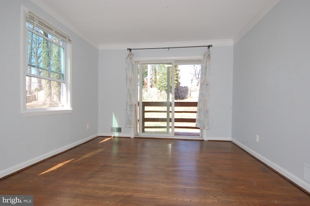 spare room featuring crown molding, wood finished floors, baseboards, and visible vents