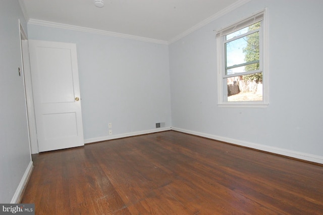 empty room featuring visible vents, crown molding, baseboards, and wood finished floors