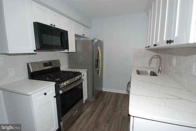 kitchen featuring dark wood-type flooring, black microwave, light stone counters, stainless steel gas stove, and a sink