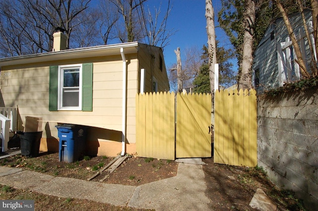 view of home's exterior with a chimney and fence