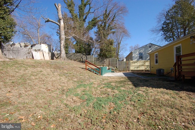 view of yard with an outbuilding, central air condition unit, and a fenced backyard