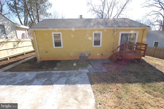 back of house with a shingled roof, fence, cooling unit, a chimney, and a patio