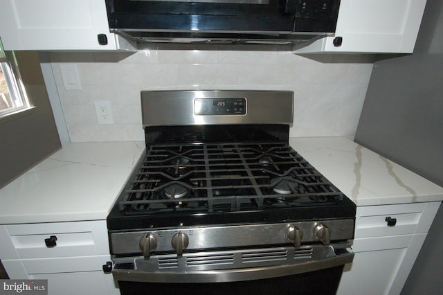 kitchen with marble finish floor, gas stove, white cabinets, decorative backsplash, and light stone countertops