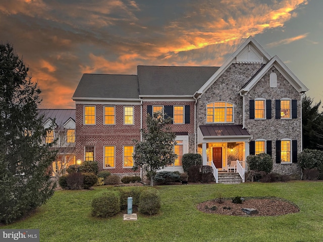 view of front of home with a front yard, brick siding, and stone siding